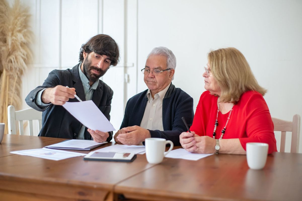 Adviser showing papers to an older couple sitting at a kitchen table