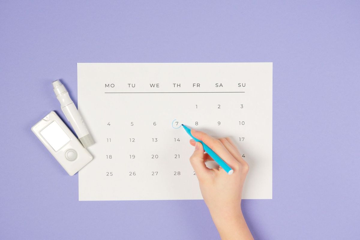 Hand drawing a circle on a paper calendar with a blue pen
