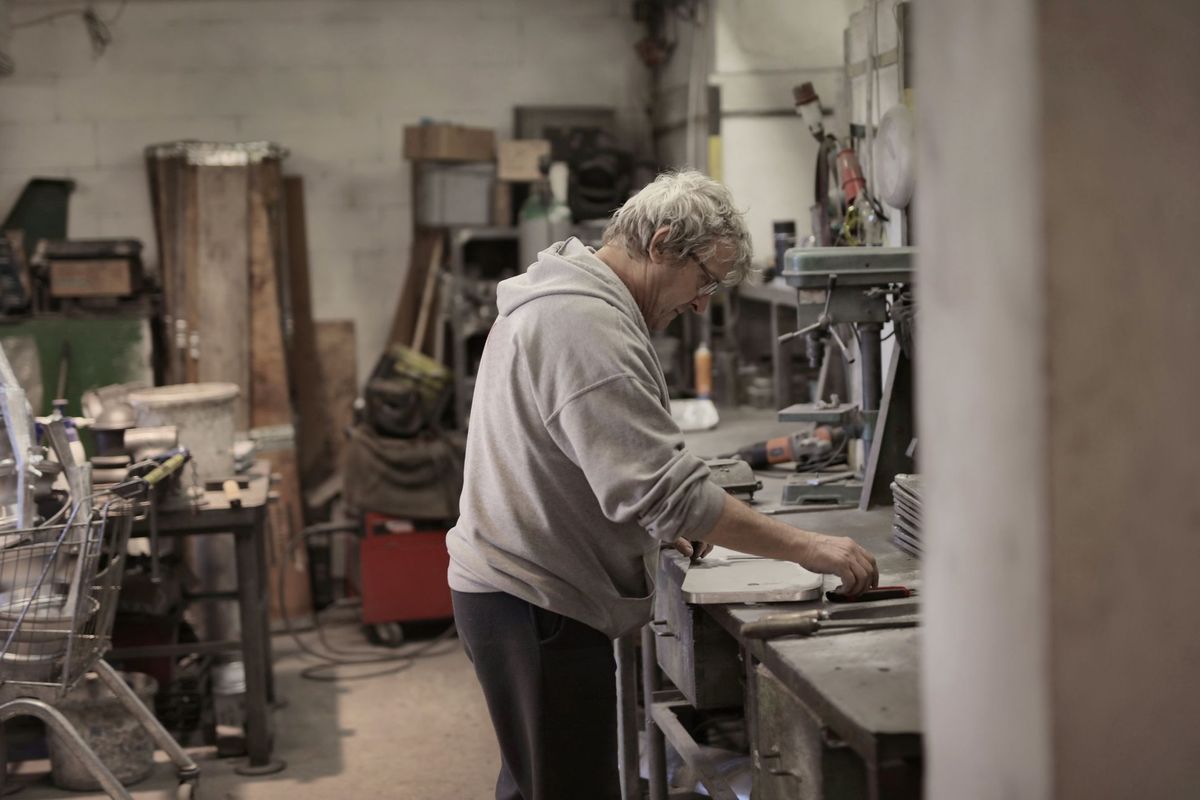 Older man working at a bench in a busy workshop